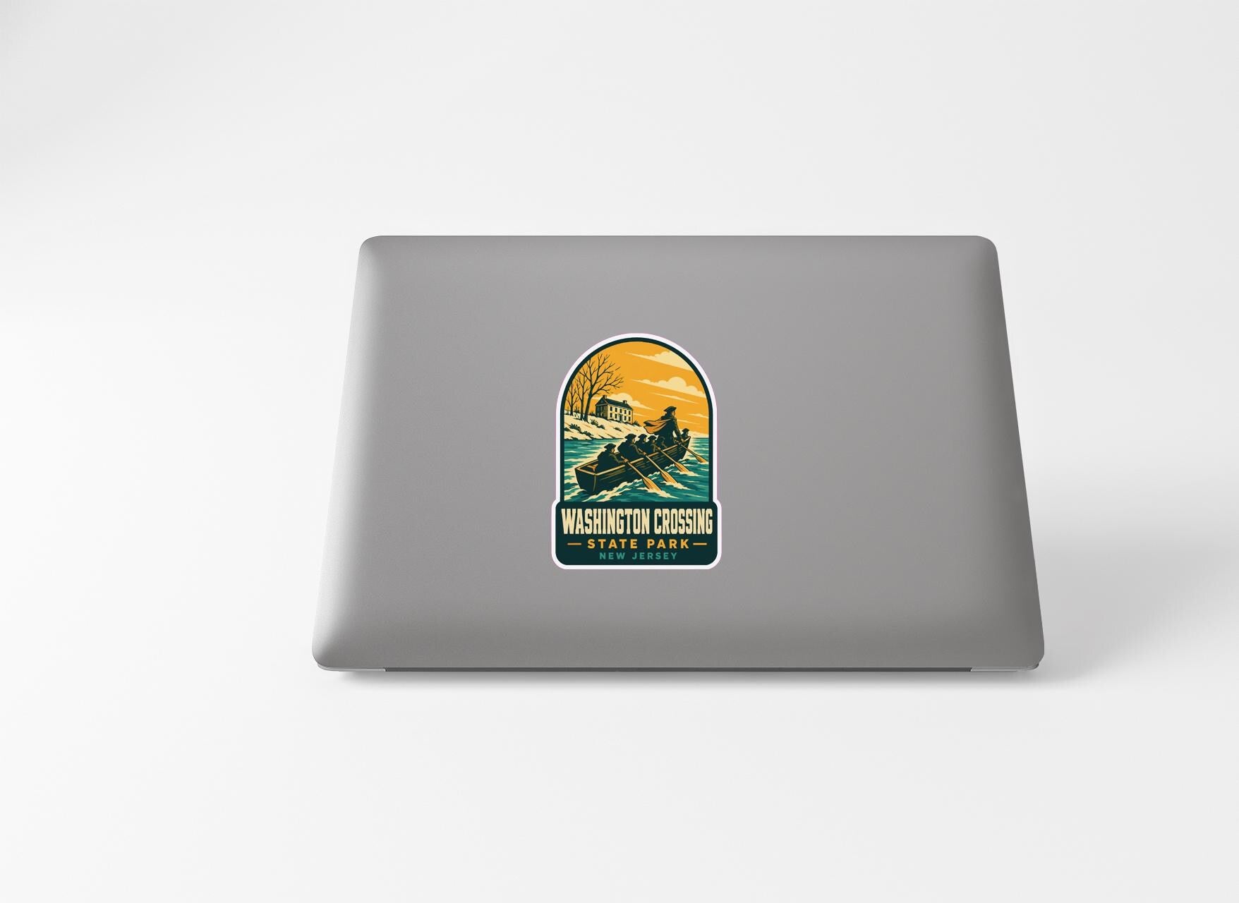 A sticker on the back of a laptop, depicting a boat on a lake with a scenic sunset in the background.