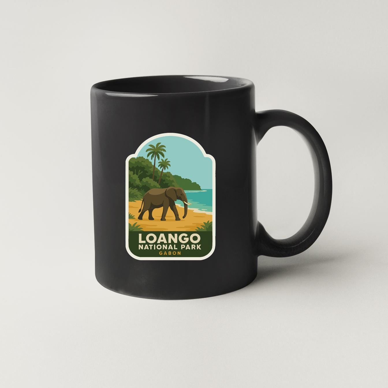 A black coffee mug with a label depicting an elephant and a tropical landscape, along with the text "Loango National Park".