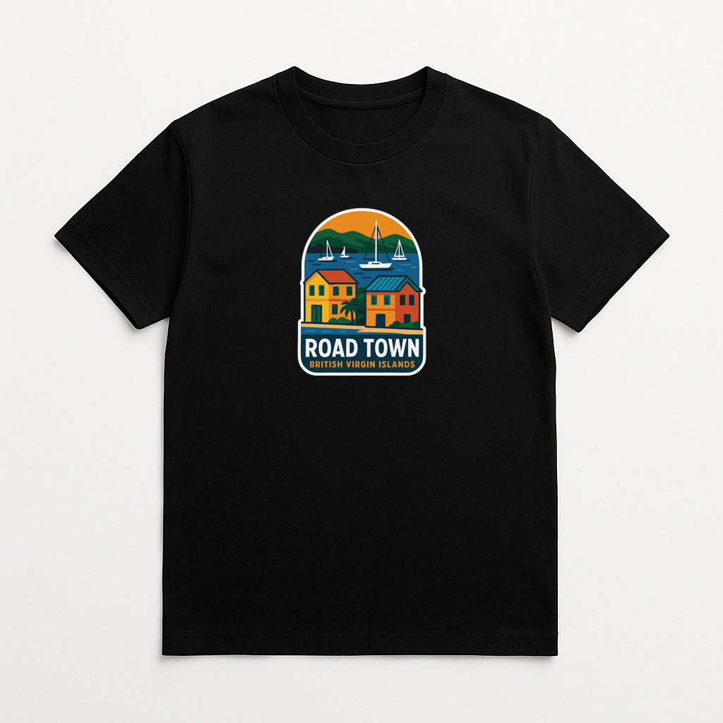 A black t-shirt with a colorful graphic design depicting a coastal town with buildings, boats, and a sunset.