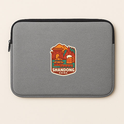 A gray laptop sleeve with a colorful logo of Shandong, China, featuring a temple, mountains, and a beer mug.