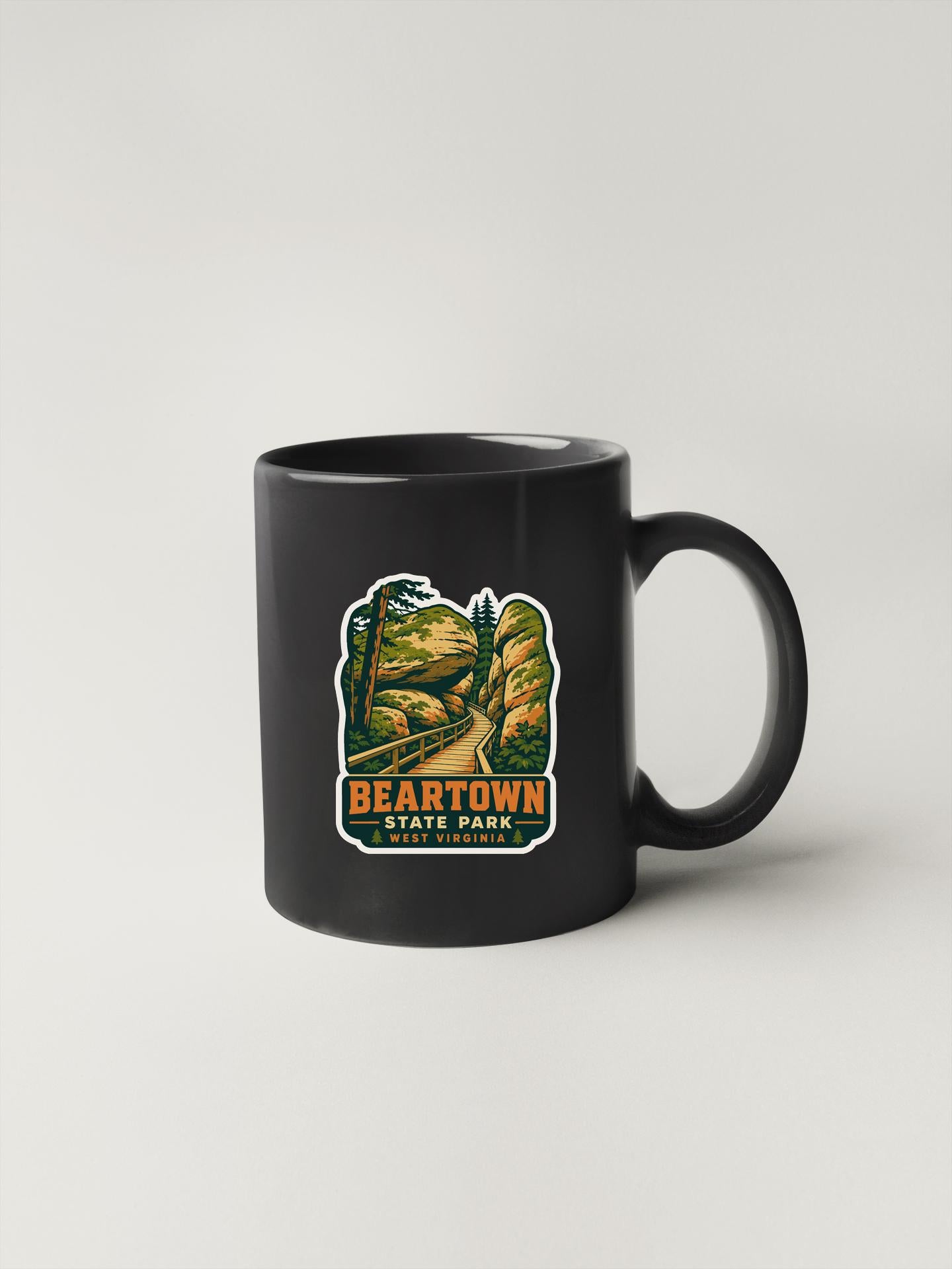 A black coffee mug with a sticker depicting a scenic landscape, including a mountain and a road, along with the text "BEARTOWN STATE PARK WEST VIRGINIA".