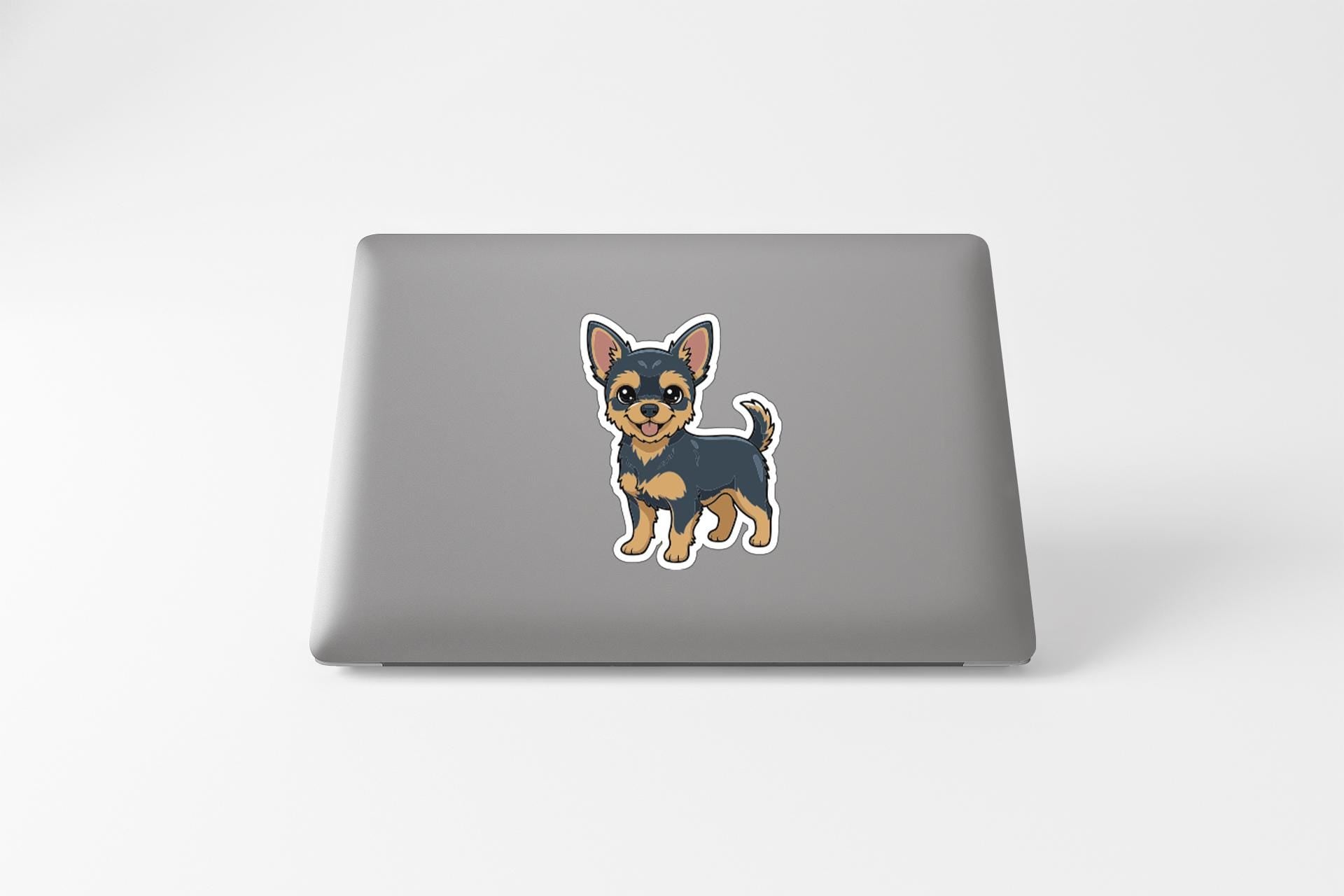A sticker of a small dog, likely a Chihuahua, is displayed on the back of a laptop computer.