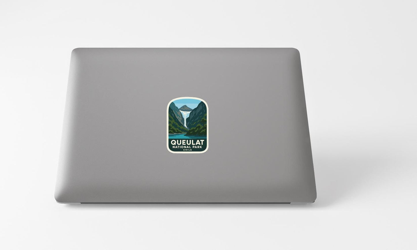 A sticker with a mountain landscape and the text "Queuelat National Park, Chile" printed on a grey laptop.