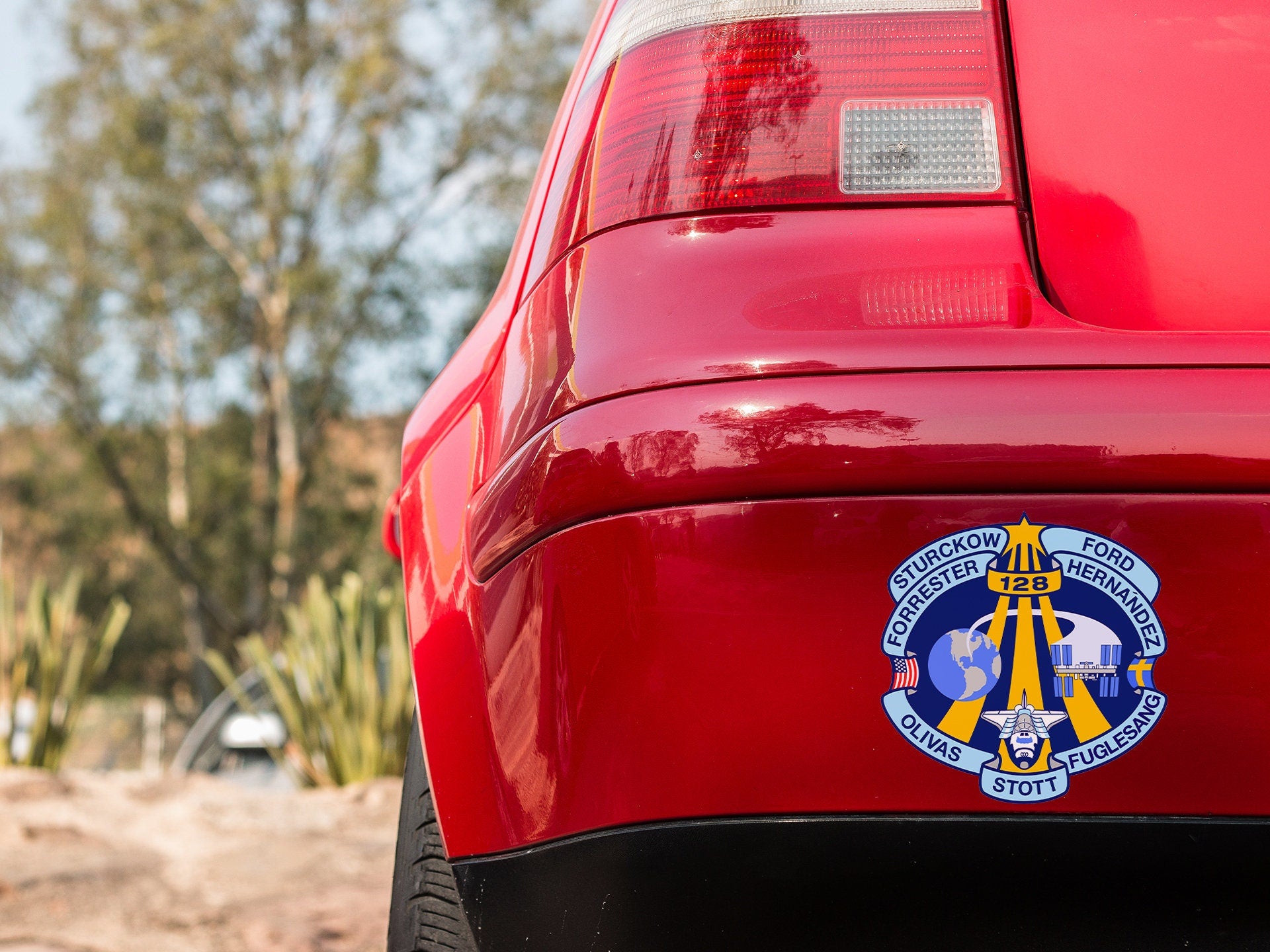 the back end of a red car with a badge on it