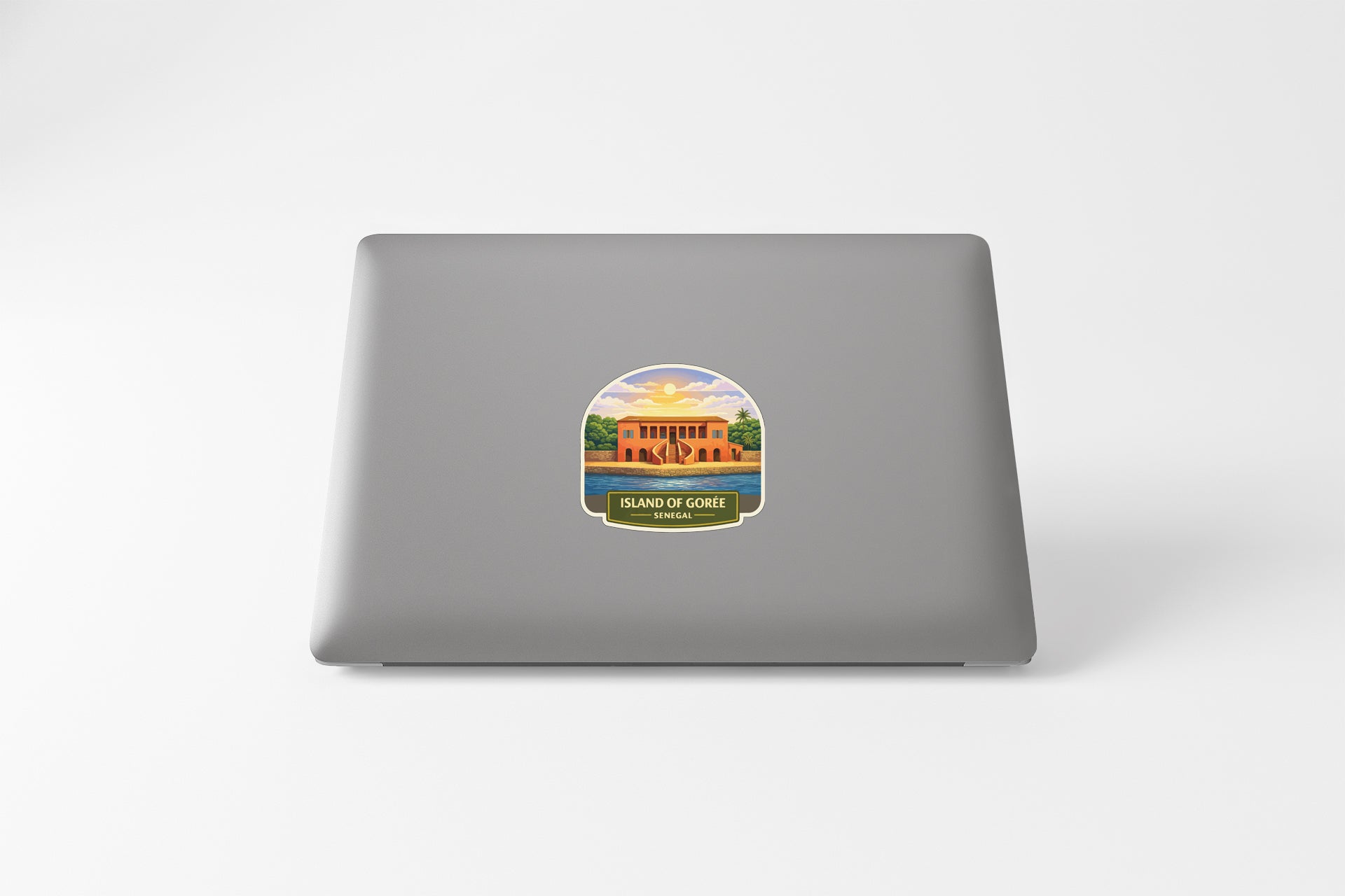 A sticker on the back of a laptop, depicting a building with a tree and a body of water.