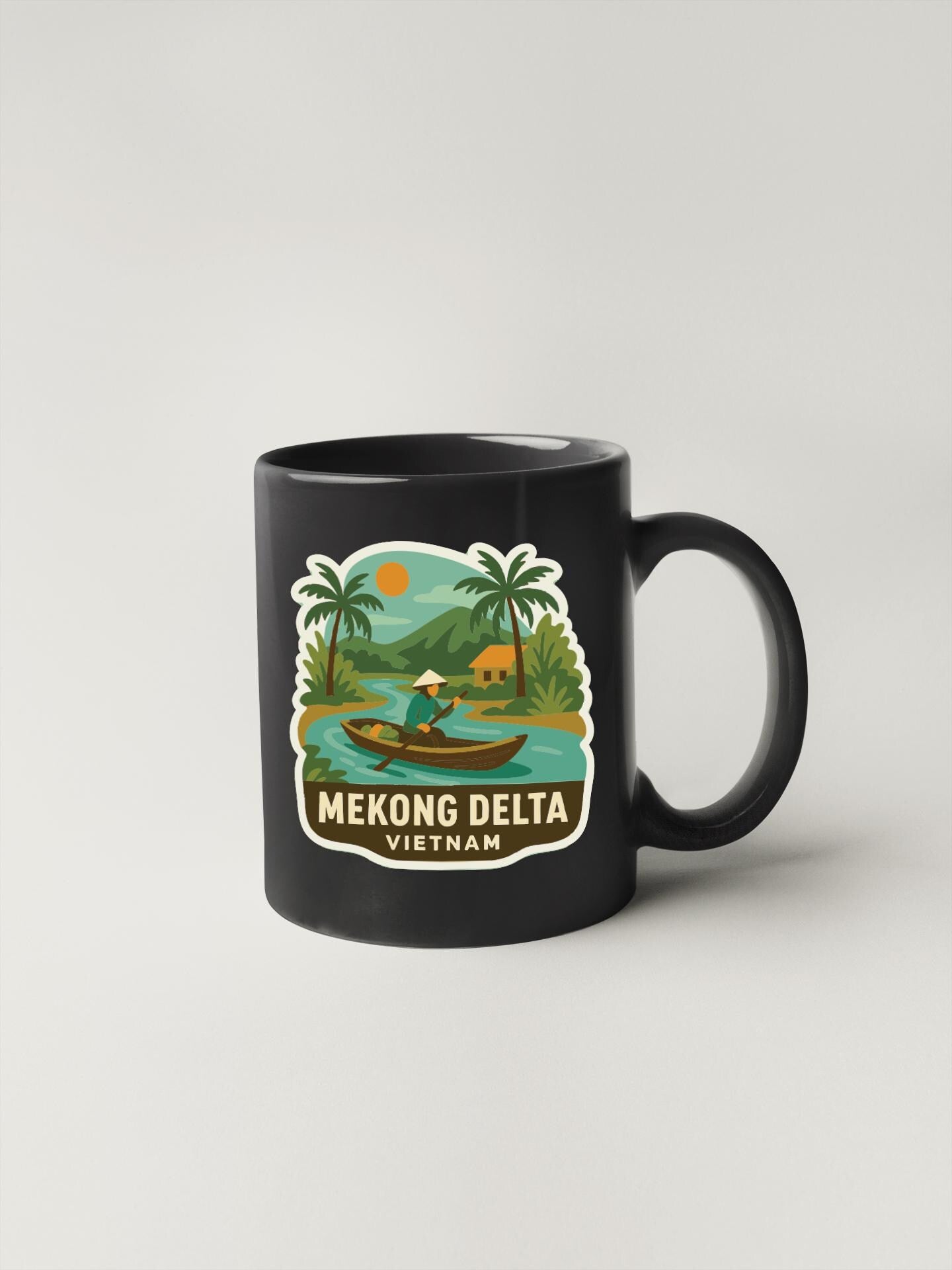 A black coffee mug with a tropical landscape and a person in a boat on the water, along with the text "Mekong Delta Vietnam".