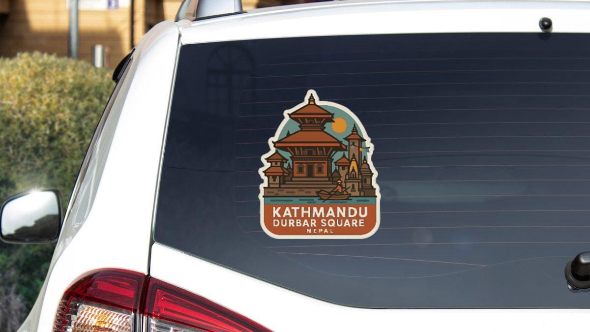 A sticker on the rear window of a car, depicting a temple with a blue sky and sun in the background.