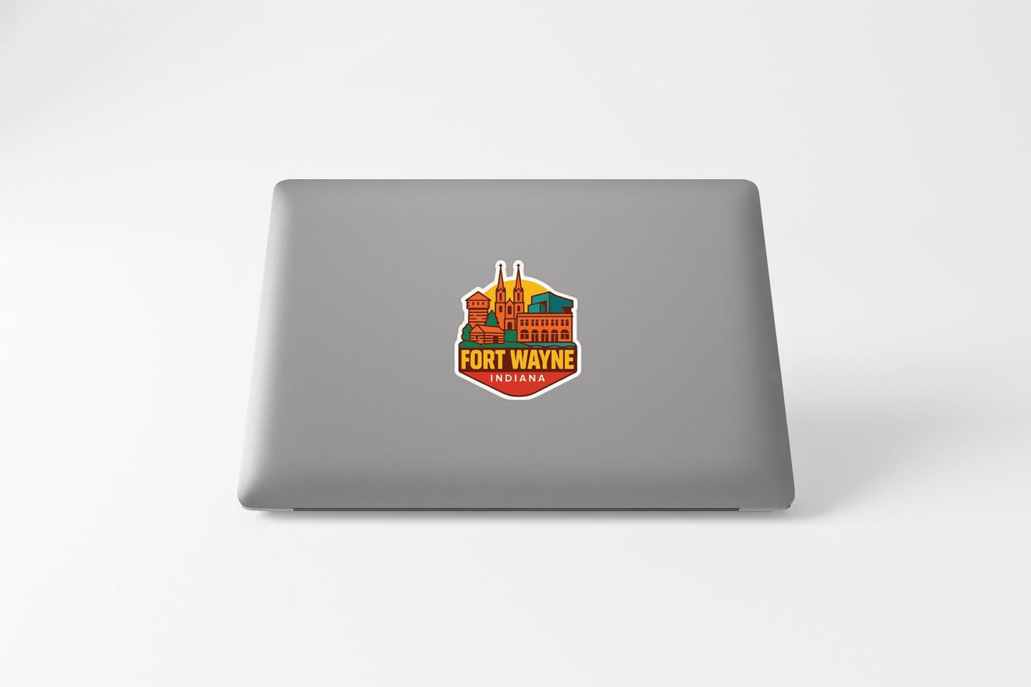 a sticker with a colorful illustration of a building and the text "FORT WAYNE" on a laptop.