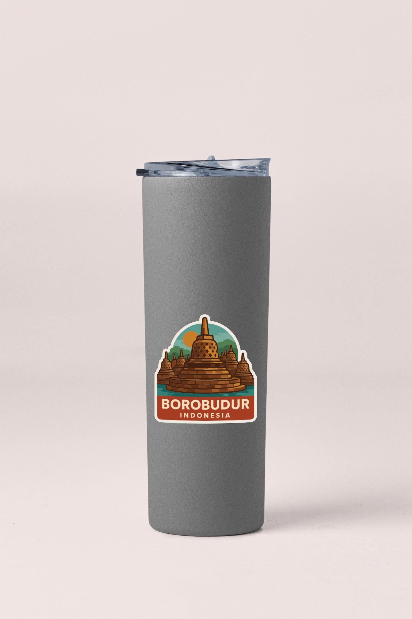A gray insulated tumbler with a sticker depicting Borobudur, a famous landmark in Indonesia.