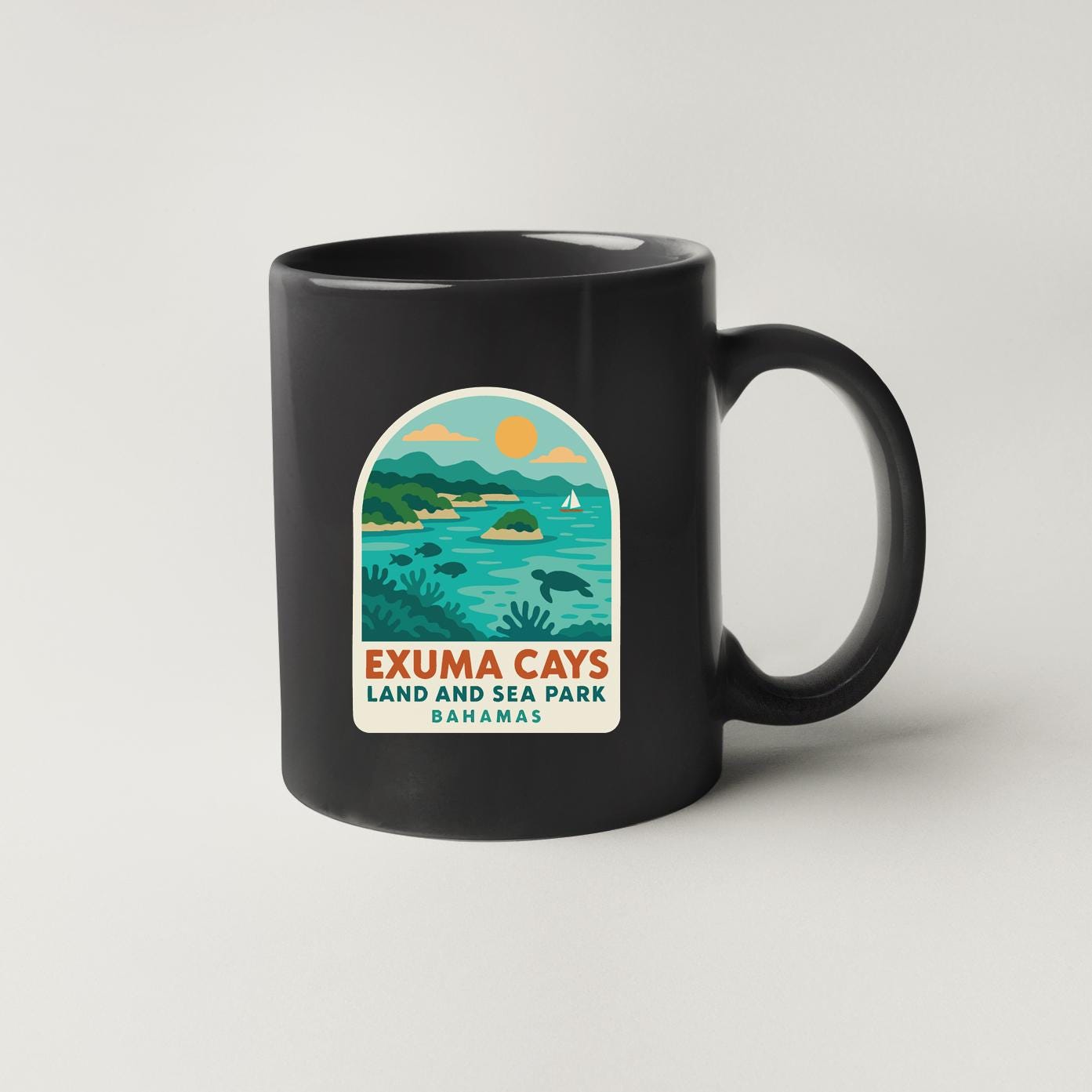 A black coffee mug with a label that says "Exuma Cays Land and Sea Park Bahamas".