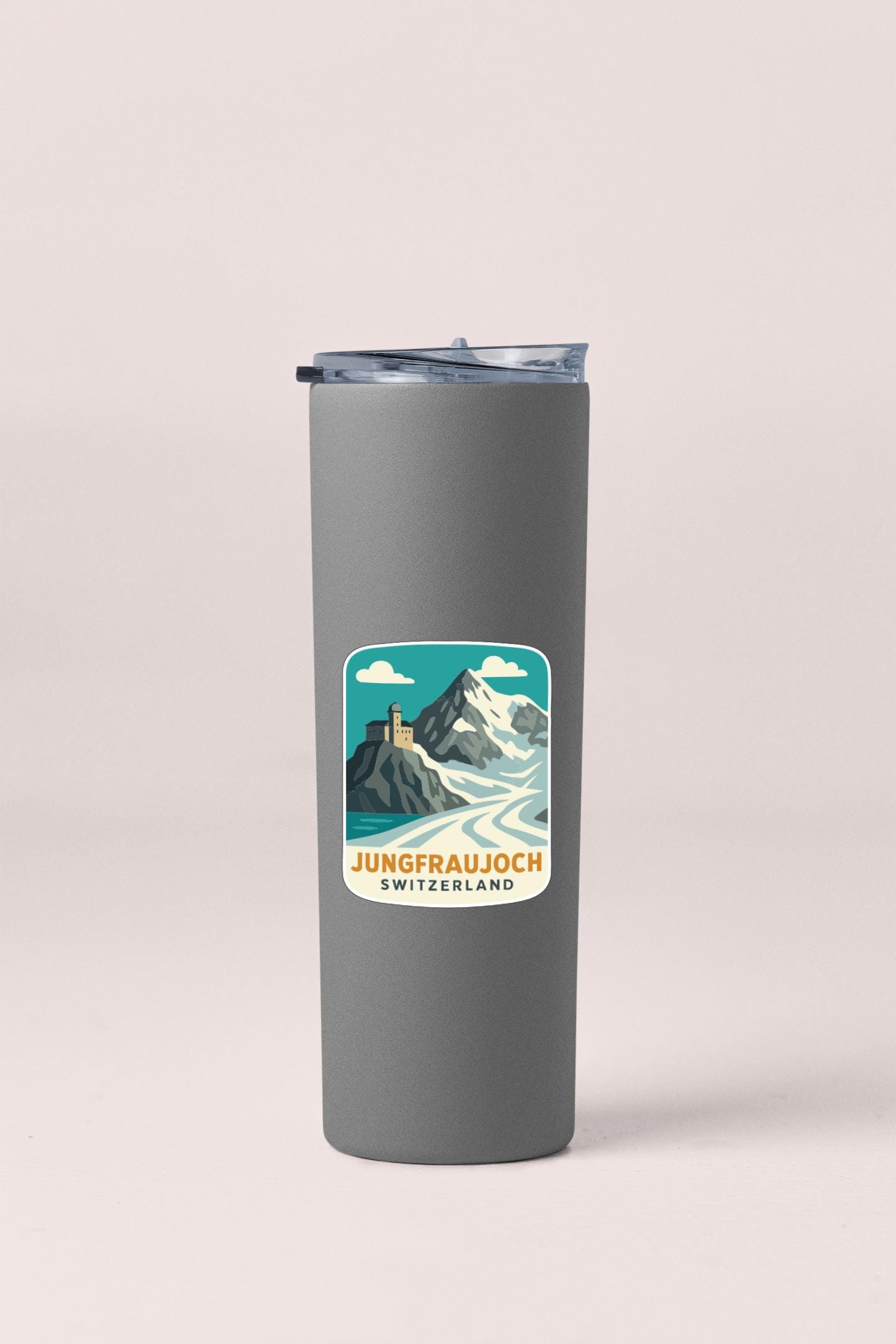 A gray insulated tumbler with a sticker depicting a mountain landscape and the text "Jungfraujoch Switzerland".