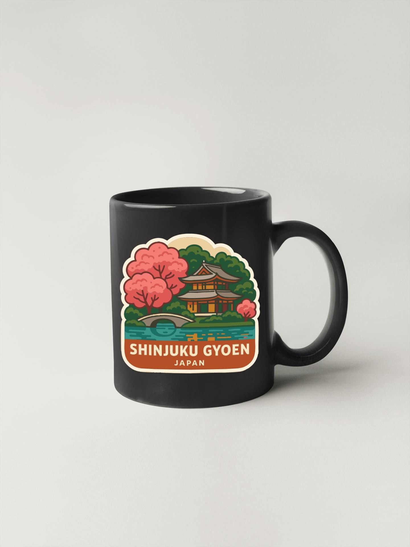 A black coffee mug with a colorful illustration of a Japanese temple and cherry blossom trees.