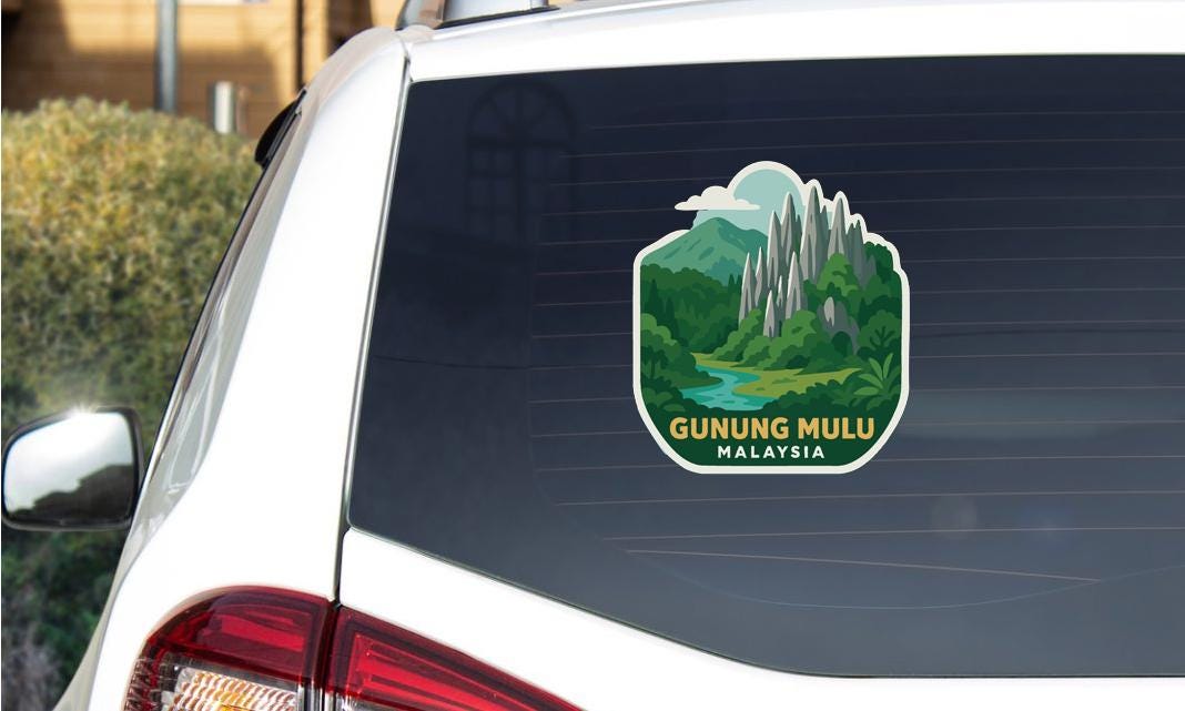 A sticker on the rear window of a car, depicting a scenic landscape with mountains and a river, with the text "GUNUNG MULU MALAYSIA".