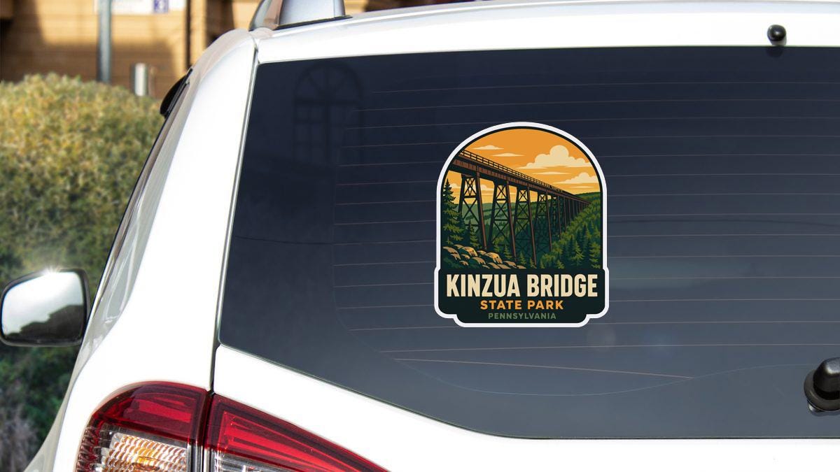 A sticker on the rear window of a white car that says "KINZU A BRIDGE STATE PARK PENNSYLVANIA".