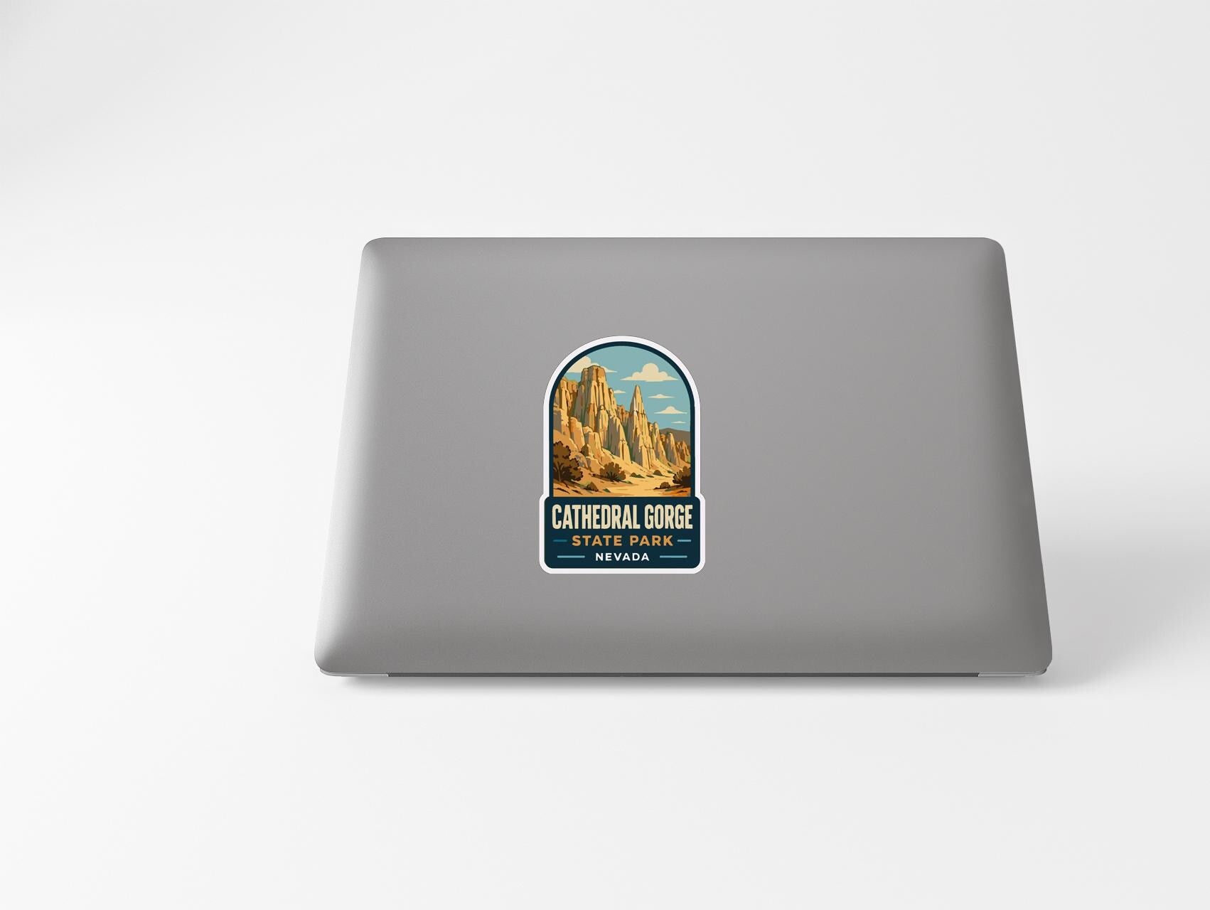 A sticker on the back of a laptop, depicting a scenic image of a mountainous landscape with the text "Cathedral Gorge State Park, Nevada" printed on it.