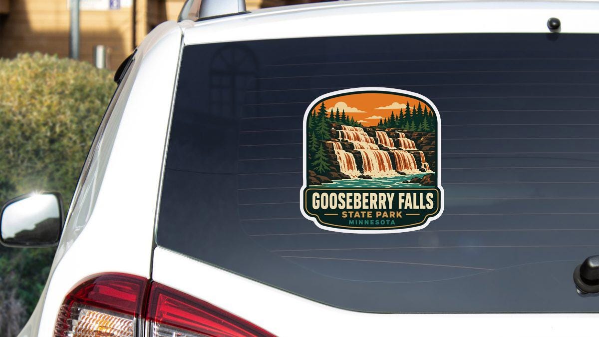 A sticker on the rear window of a white car, depicting a scenic waterfall surrounded by trees and mountains.