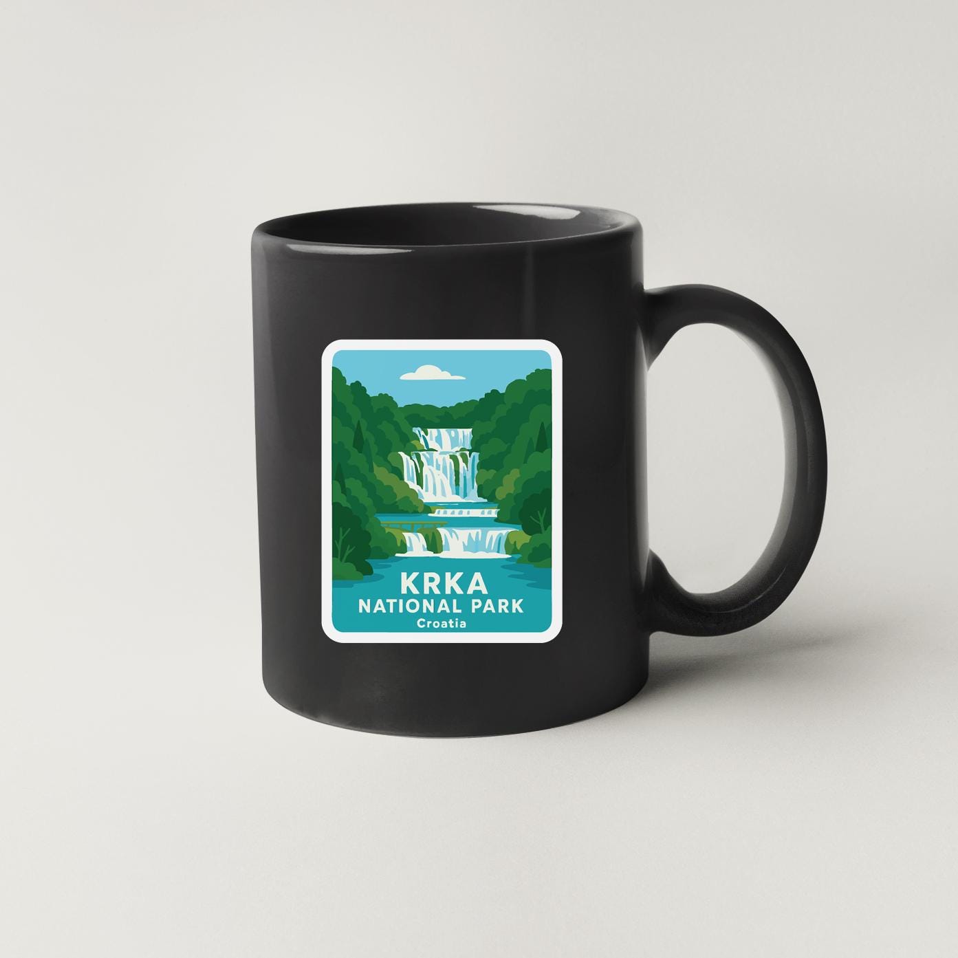 A black coffee mug with a sticker depicting a waterfall and the text "KRKA NATIONAL PARK, Croatia".