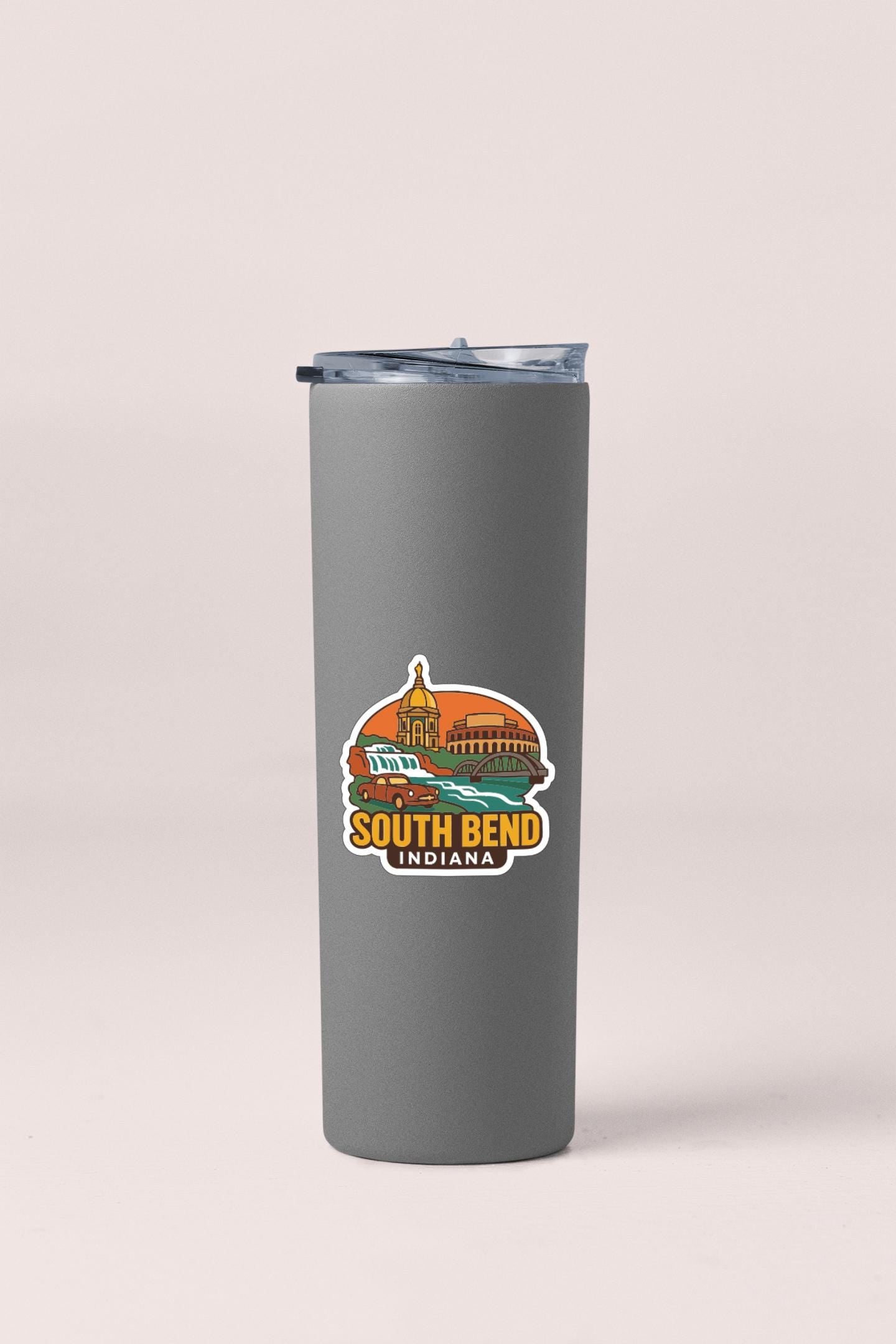 A gray insulated tumbler with a lid and a sticker depicting a city skyline and the text "SOUTH BEND, INDIANA".