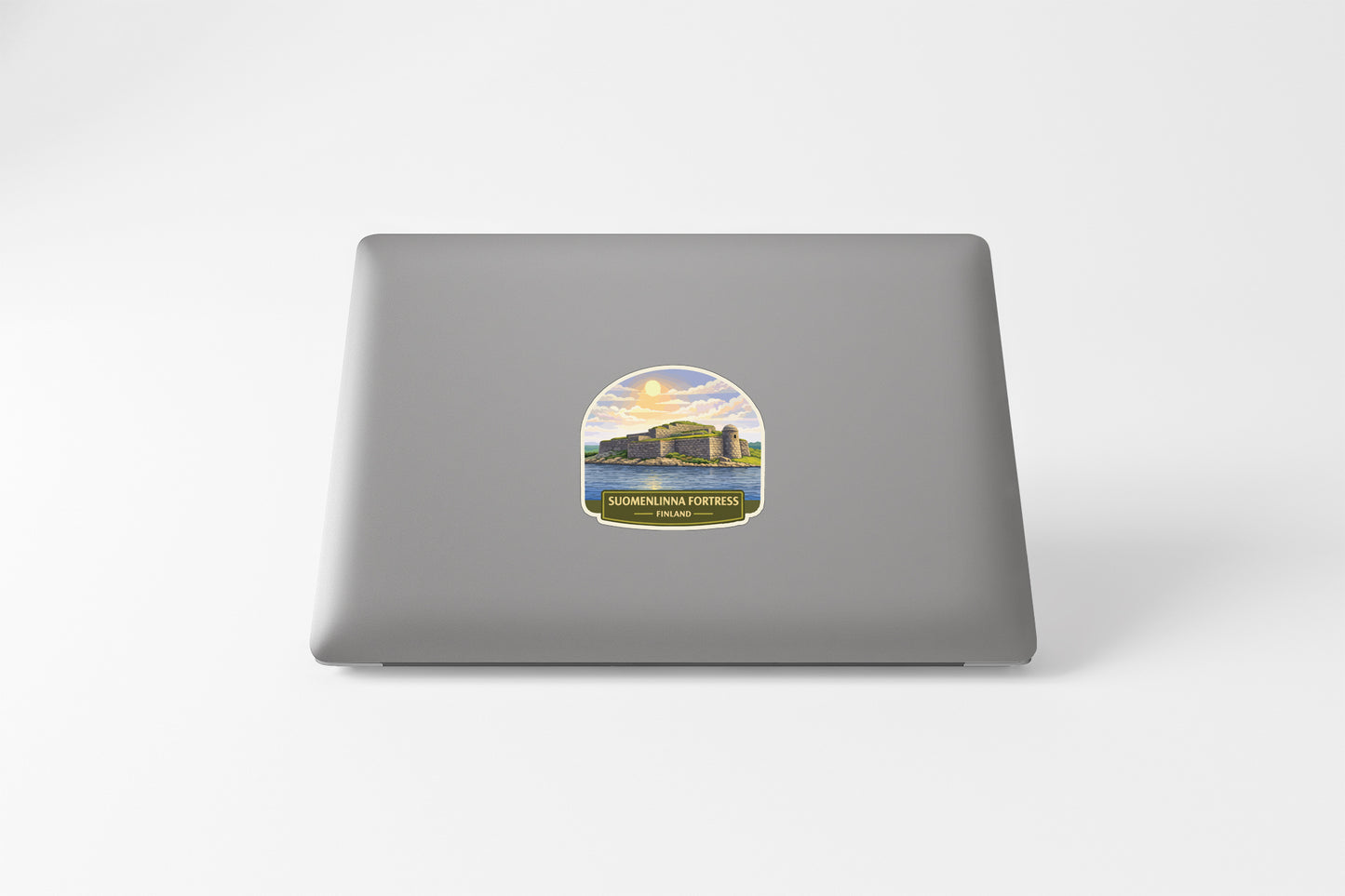 A sticker on the back of a laptop, depicting a scenic landscape with a castle or fortification in the background.