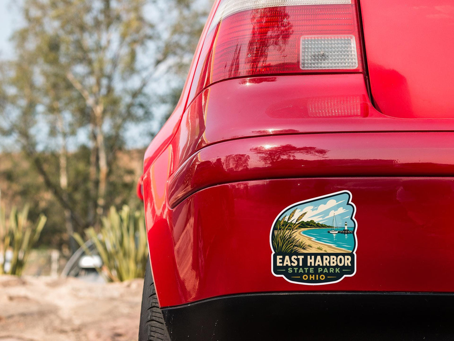 the rear end of a red car with a sticker on the back window that reads "East Harbor State Park, Ohio".