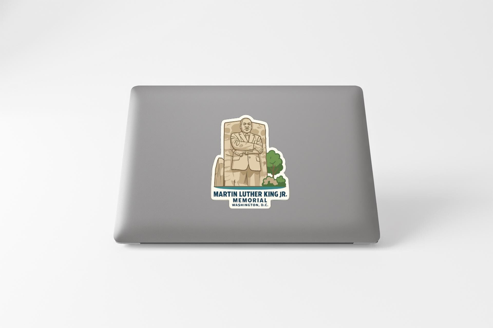 A sticker on the back of a laptop featuring an illustration of Martin Luther King Jr. and the text "Martin Luther King Jr. MEMORIAL WASHINGTON, D.C."