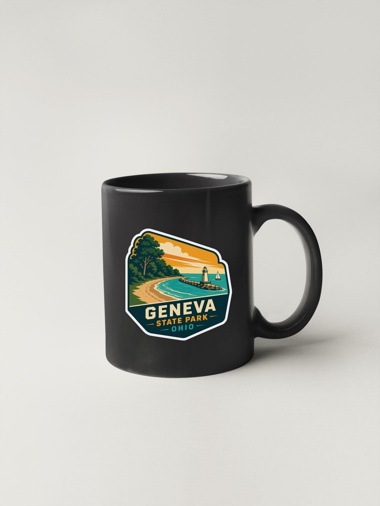 A black coffee mug with a sticker depicting a scenic view of Geneva State Park in Ohio.