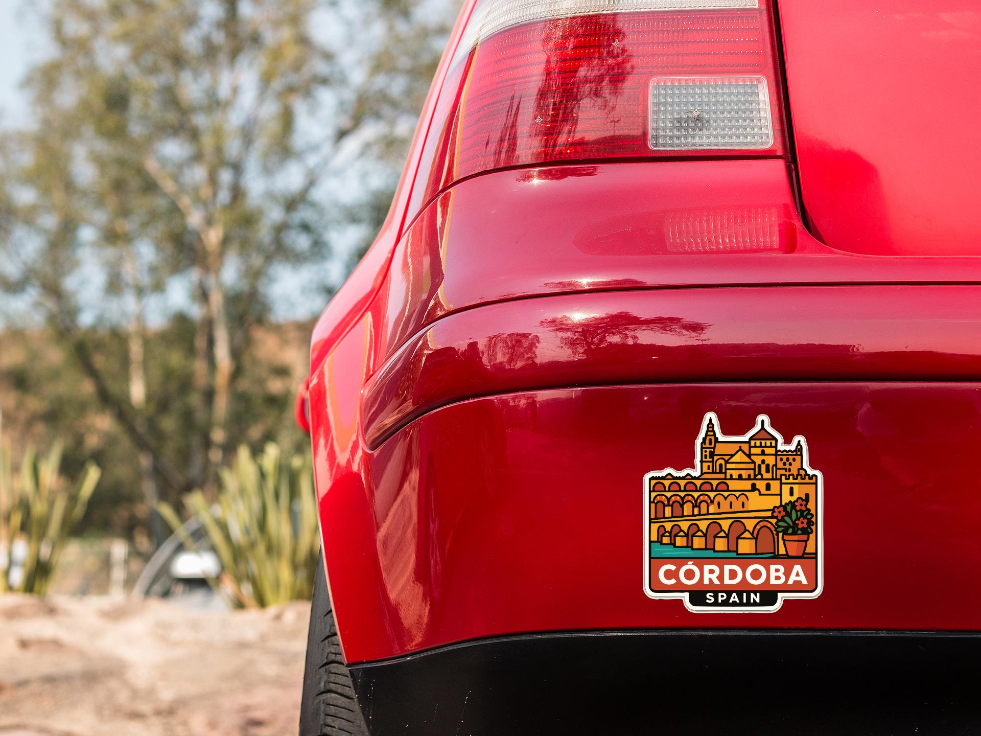 the rear end of a red car with a sticker on the trunk that says "Cordoba Spain".