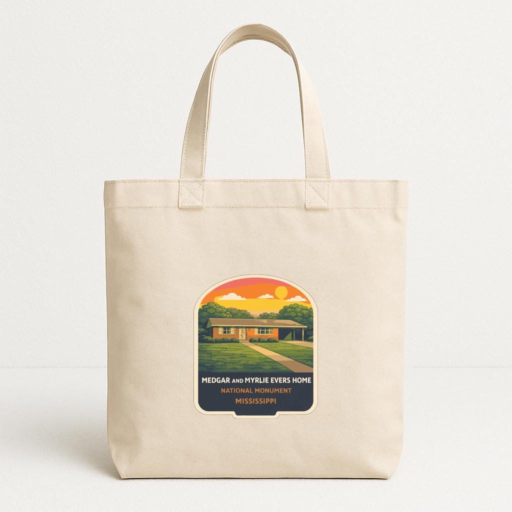 A beige tote bag with a printed design depicting a house and trees, along with text that reads "PEDGAR AND MY TRUE EVERHOME NATIONAL MONUMENT MISSISSIPPI".