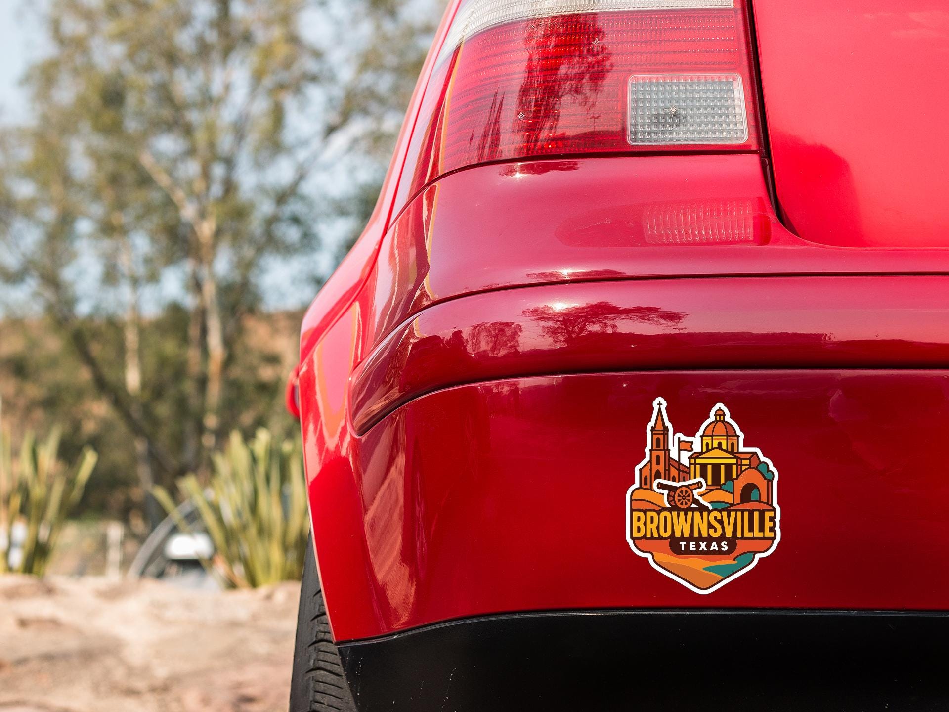 the rear end of a red car with a sticker on the trunk that says "Brownsville, Texas".