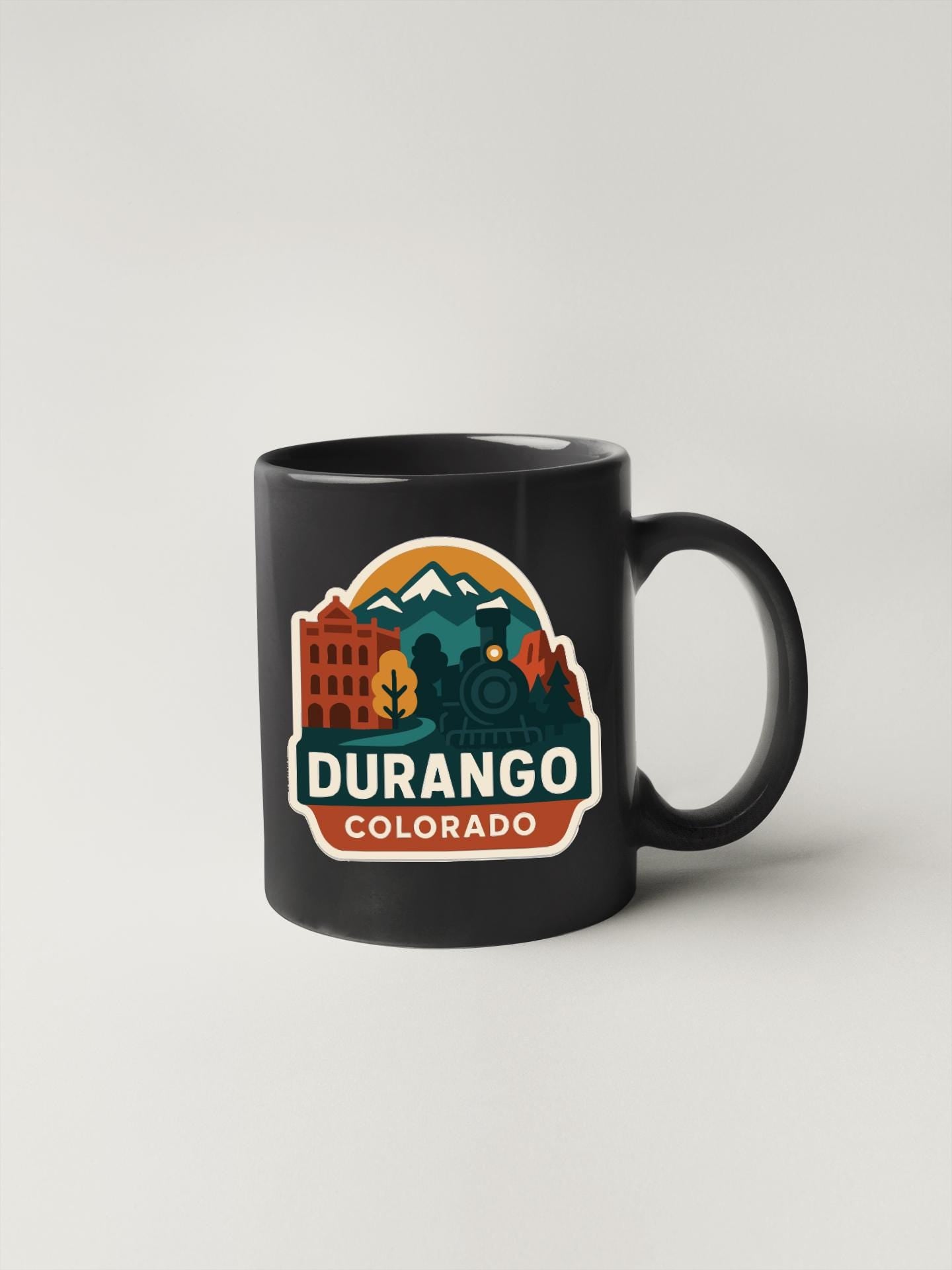 A black coffee mug with a colorful graphic design featuring the text "DURANGO COLORADO" and various elements representing the state of Colorado.