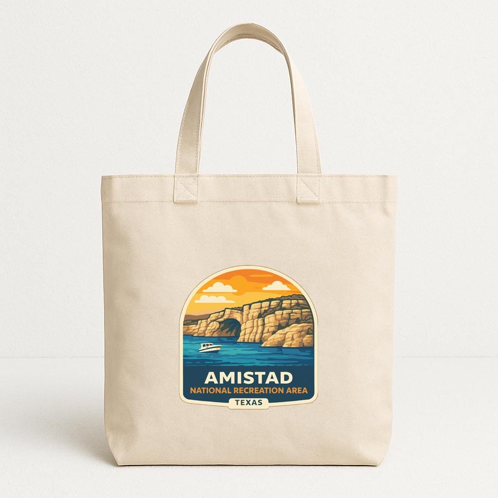 A beige tote bag with a graphic design depicting a scenic landscape, including a body of water, cliffs, and a boat.