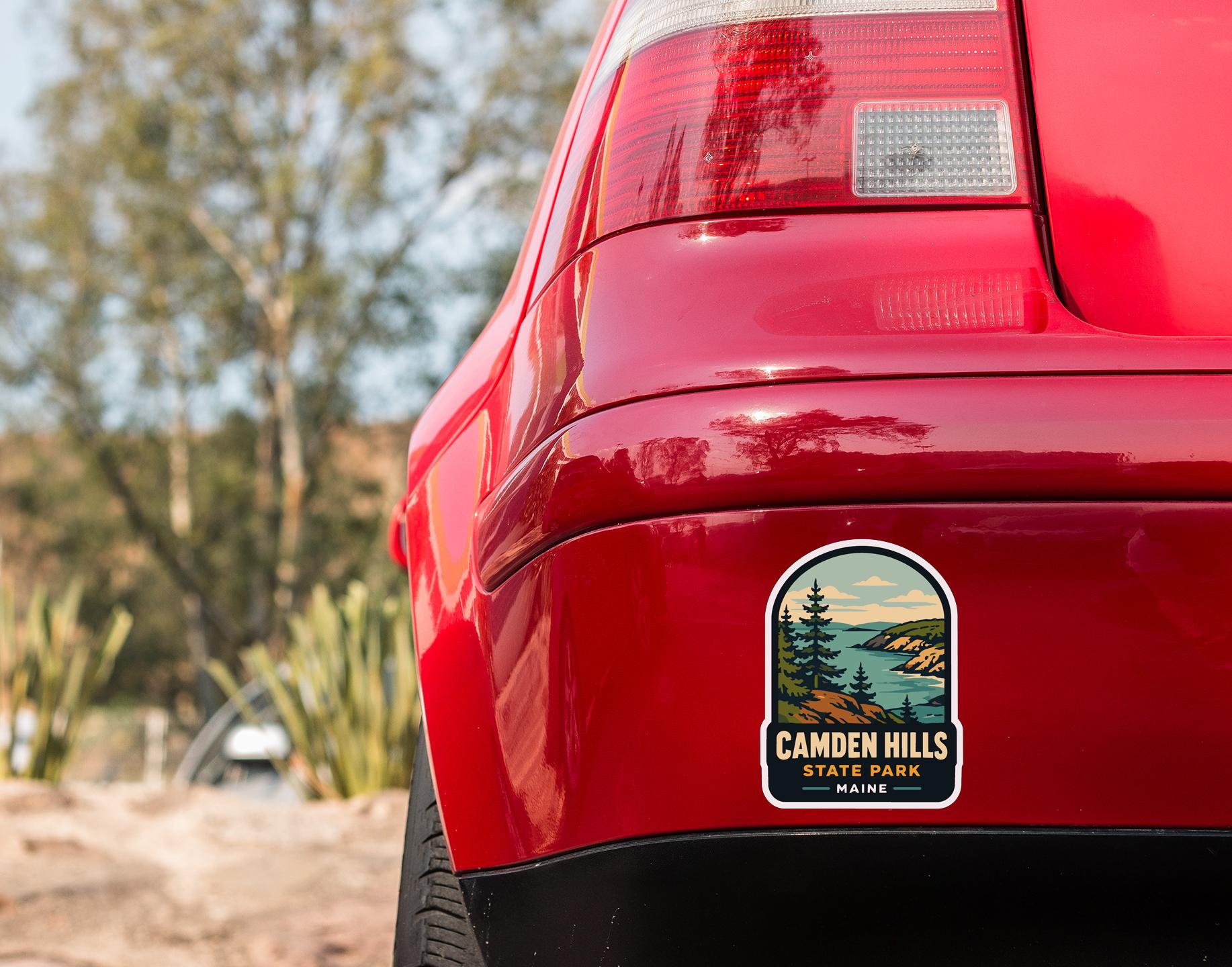 the rear end of a red car with a sticker on the trunk that reads "CAMDEN HILLS STATE PARK Maine".