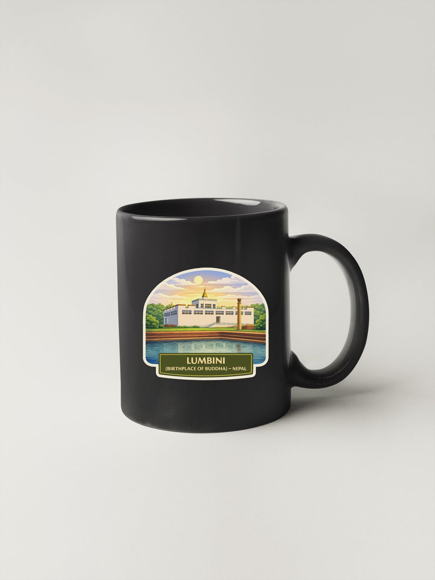 A black coffee mug with a label depicting a building and a body of water, along with the text "LUMBIN" and "BORN IN BUDHEPATHI - NEPAL".