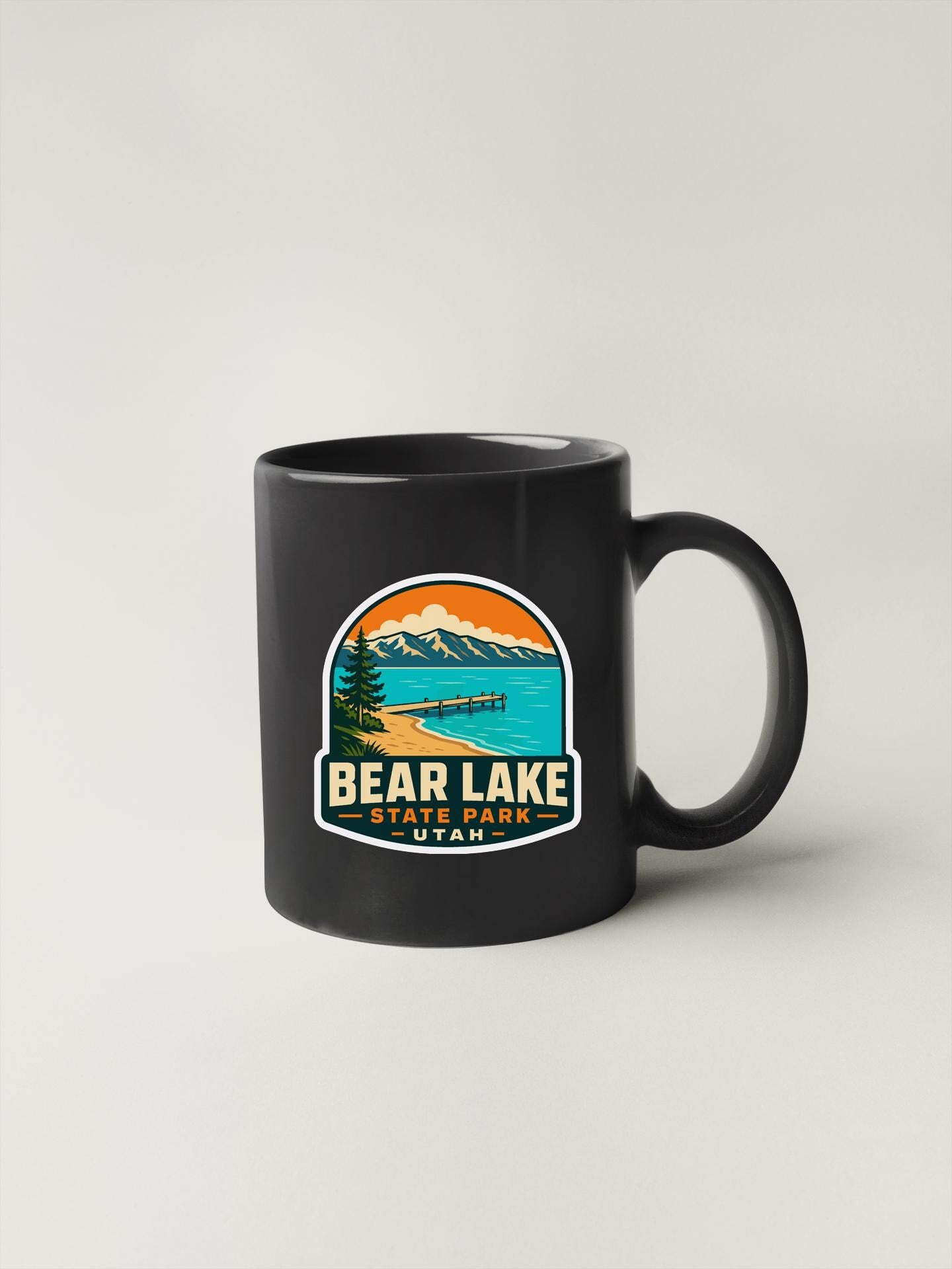 A black coffee mug with a graphic design depicting Bear Lake State Park in the background.