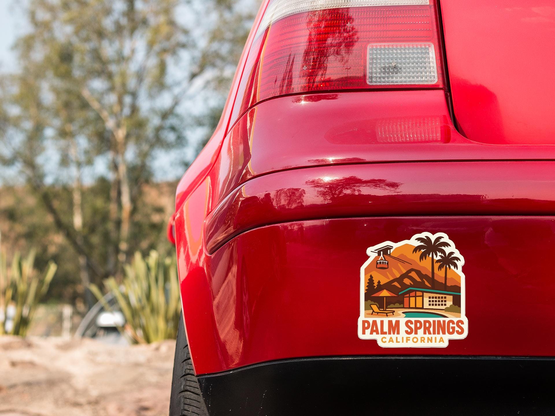 the rear end of a red car with a sticker on the trunk that says "Palm Springs, California".