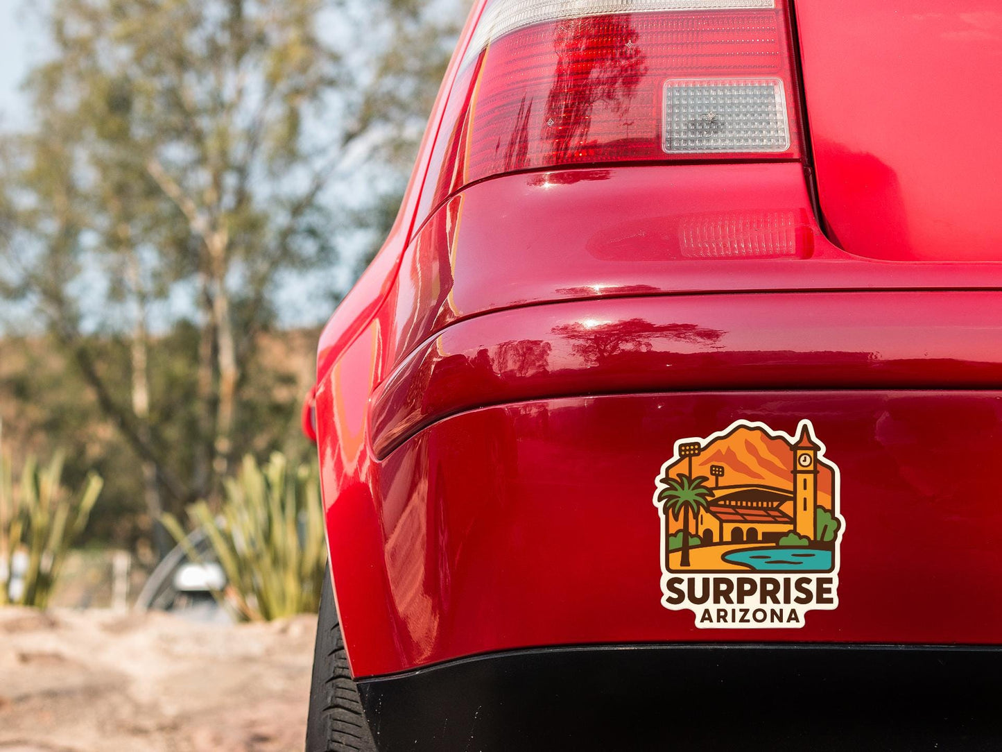 the rear end of a red car with a sticker on the trunk that says "Surprise Arizona".