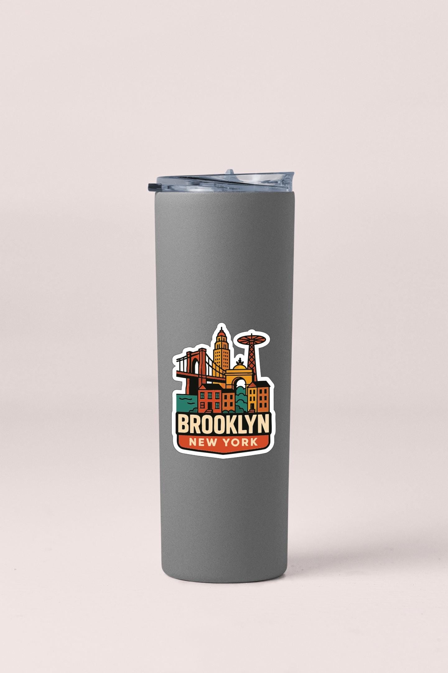 A gray tumbler with a sticker depicting the skyline of Brooklyn, New York.
