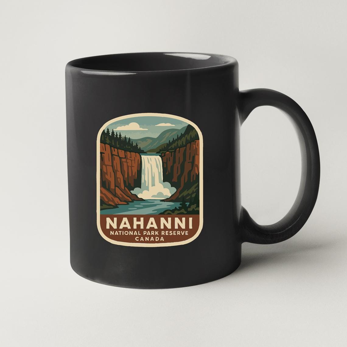 A black coffee mug with a vintage-style illustration of the Nahanni National Park Reserve in Canada.