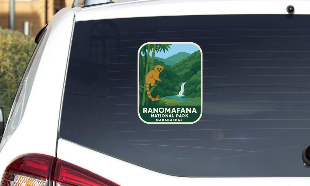 a sticker on the rear window of a vehicle, depicting a lemur in a tropical forest setting.