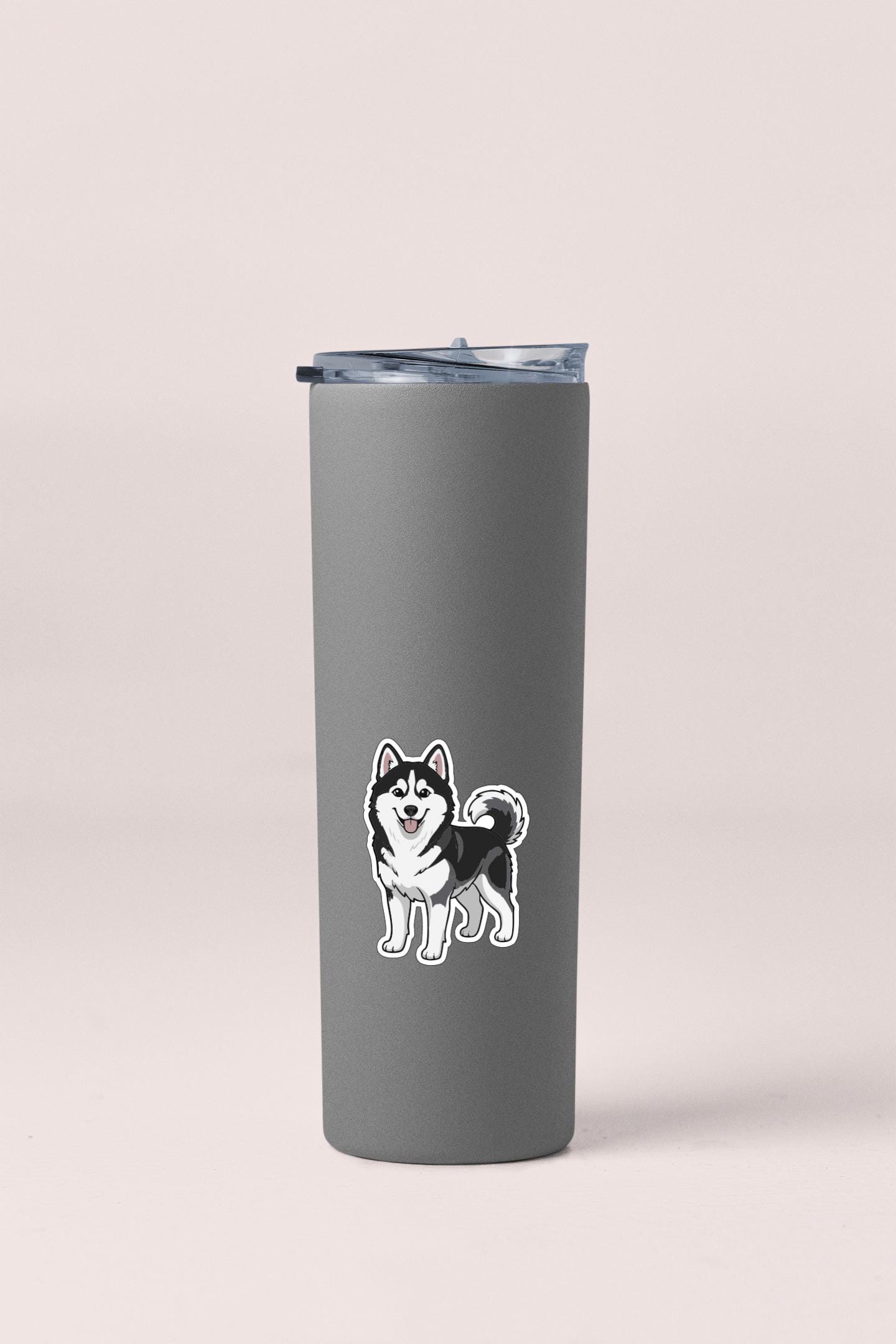 A gray insulated tumbler with a sticker of a husky dog on it.