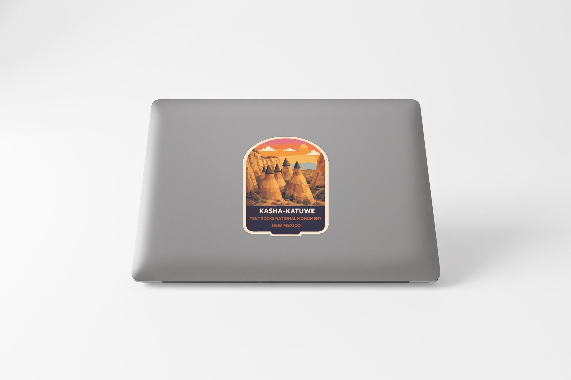 A sticker on the back of a laptop, depicting a desert landscape with mountains and a sunset.