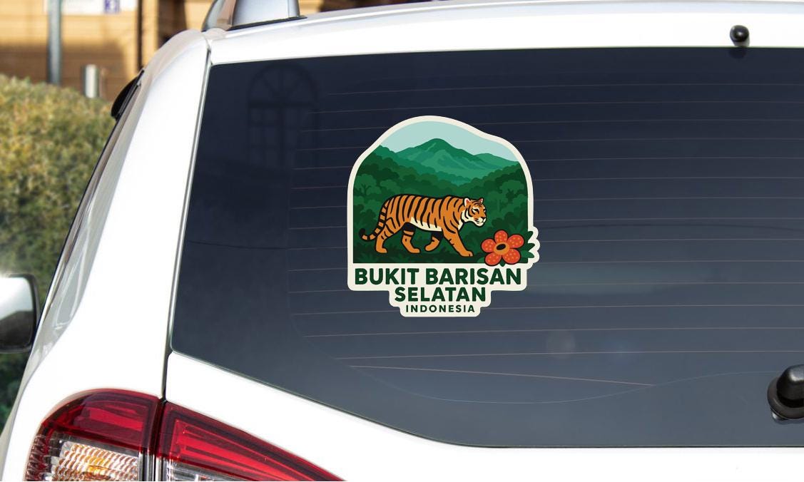 a sticker on the rear window of a car, depicting a tiger walking through a forest landscape with mountains in the background.