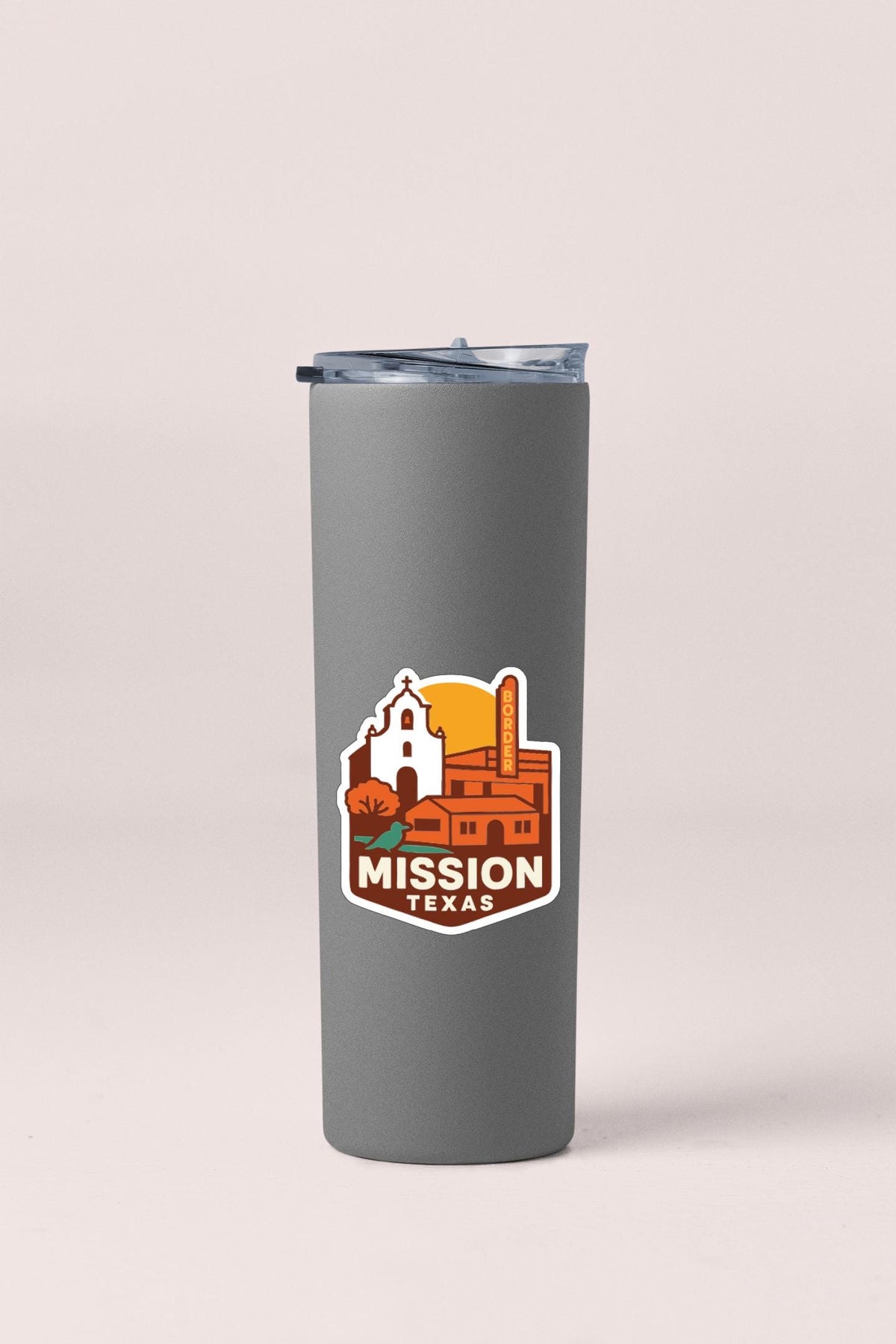 A gray tumbler with a sticker depicting a cityscape and the text "MISSION TEXAS" printed on it.