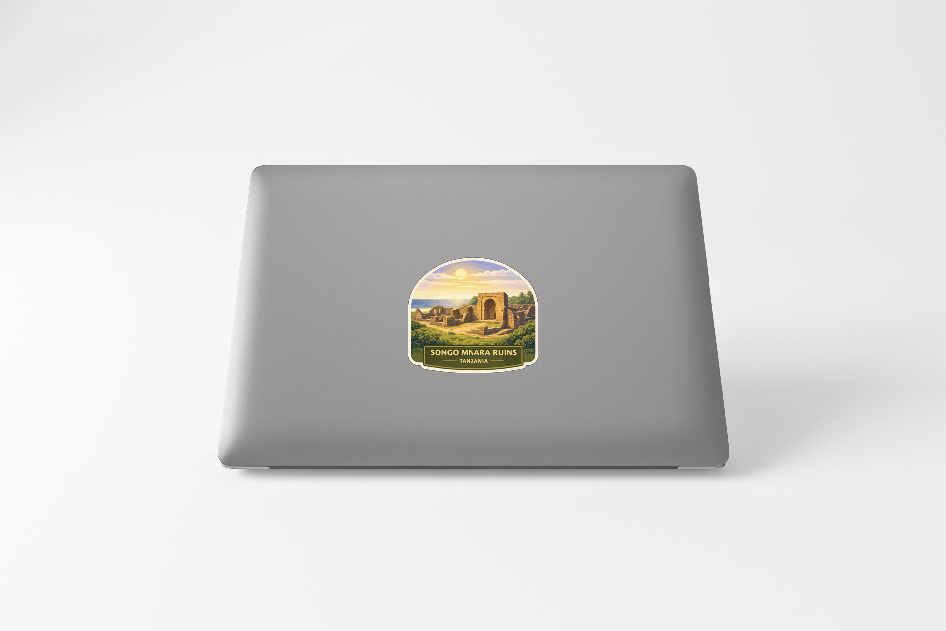 a sticker on the back of a laptop, depicting a scenic landscape with a castle or monument in the background.
