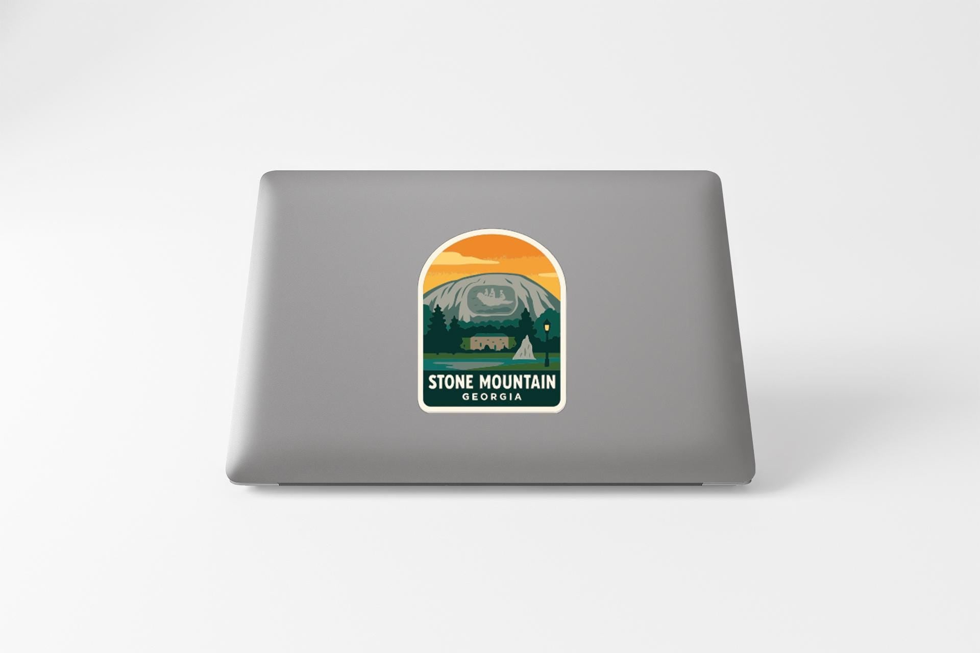 a sticker with a mountain landscape and the text "STONE MOUNTAIN GEORGIA" on the back of a laptop.