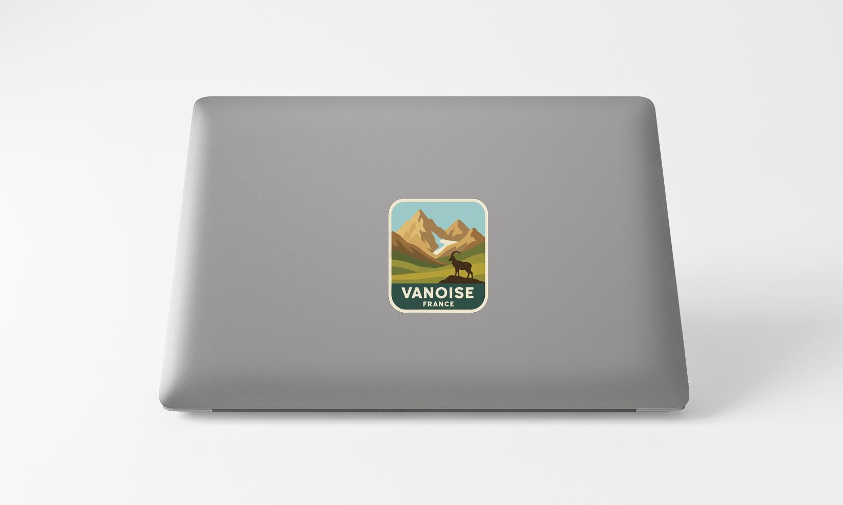 a sticker with a mountain landscape and a goat on a laptop.