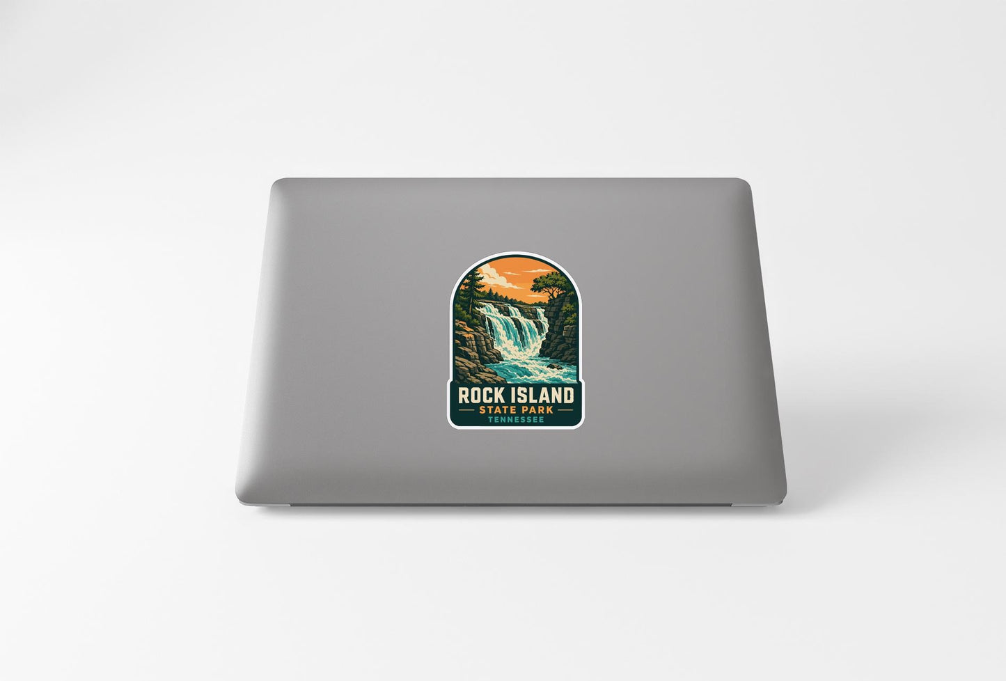 A sticker depicting a waterfall and forest on the back of a laptop computer.