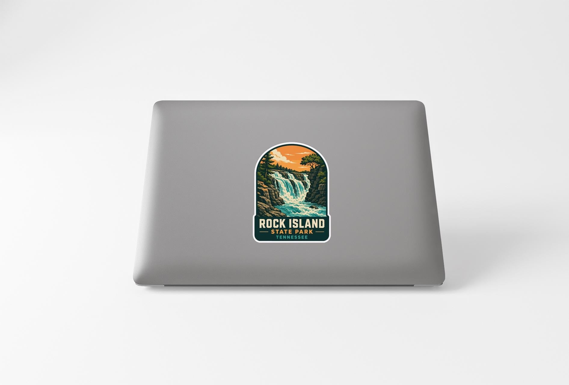 A sticker depicting a waterfall and forest on the back of a laptop computer.