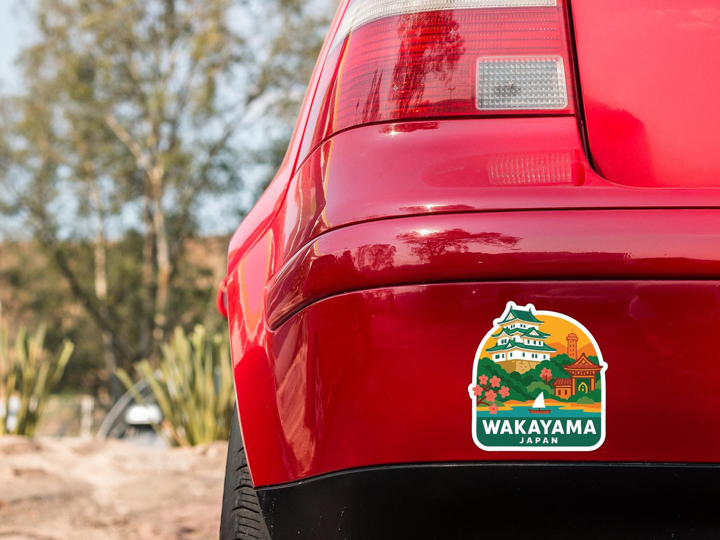 the rear end of a red car with a sticker on it, featuring a scenic image of a Japanese temple and landscape.