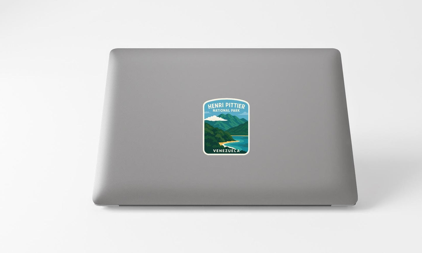 A sticker on the back of a laptop, depicting a scenic mountain landscape with a river and a small town in the distance.